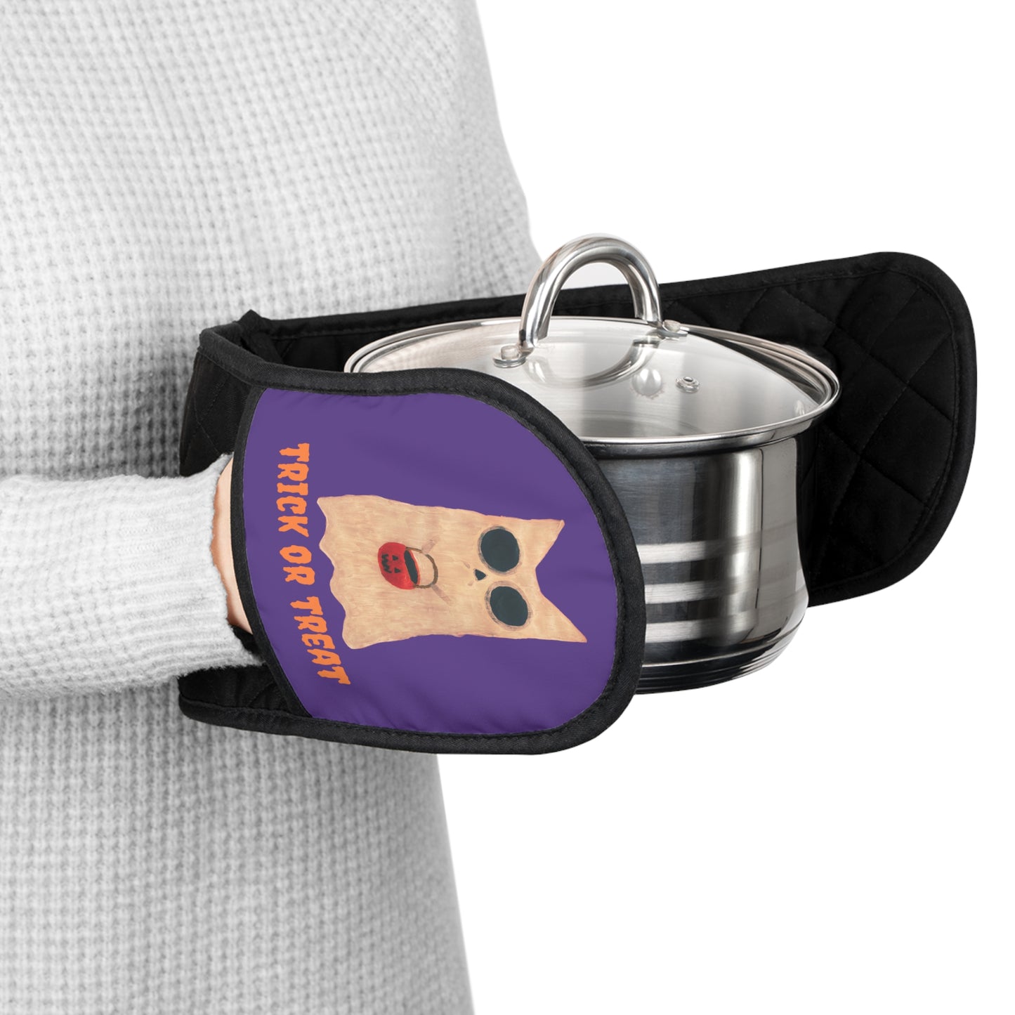 Person holding a pot with an oven mitt featuring a "Trick or Treat" Halloween design.